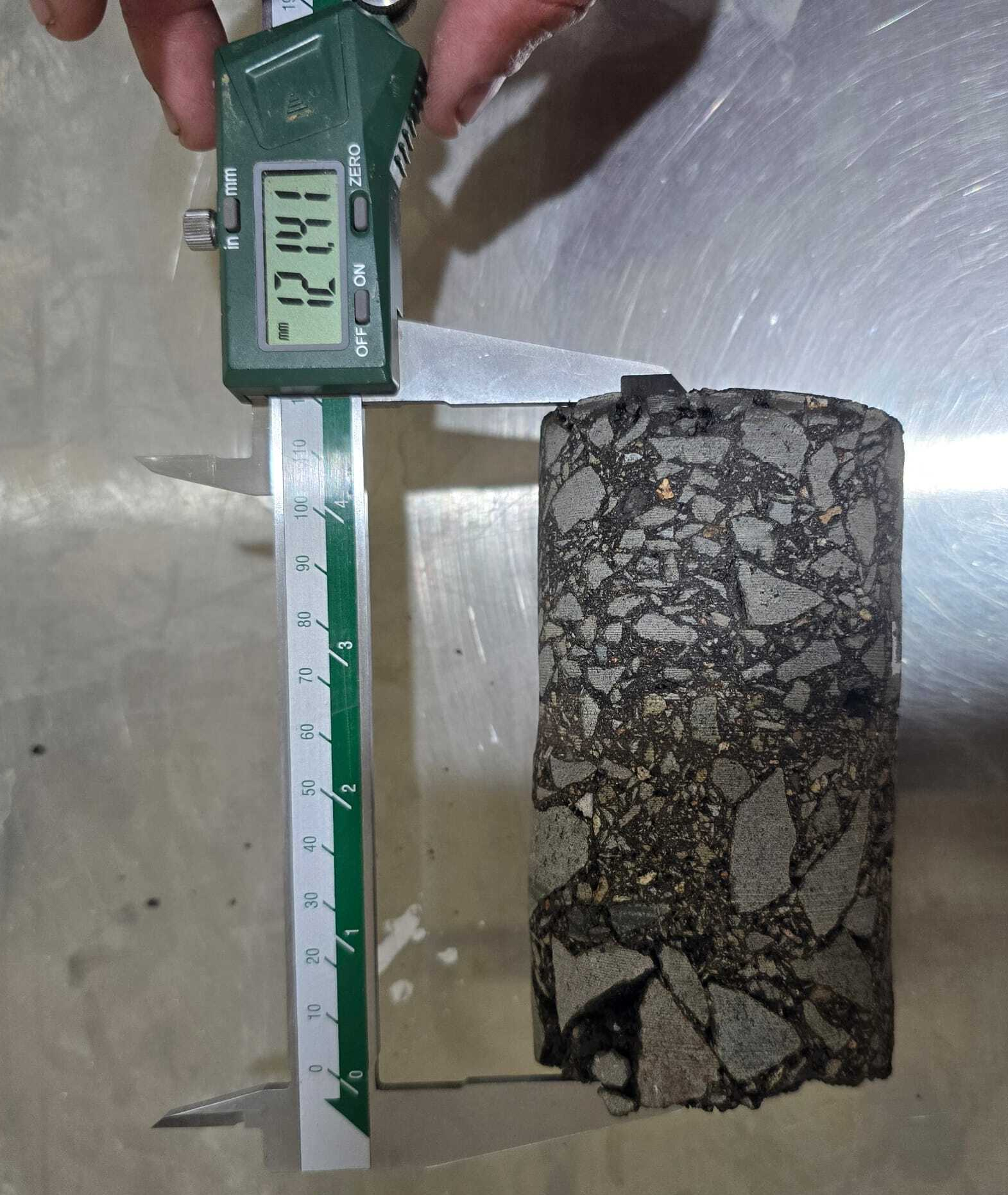 Asphalt core being measured with digital calipers in laboratory